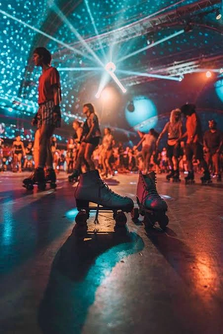 Skate inspiration: roller skates on a floor with dancers and colorful lights in the background